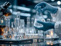 Scientist in protective gloves holding glass flask in modern laboratory setting with microscope and research equipment. Dark blue toned scientific research scene.