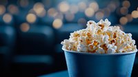 Fresh popcorn overflowing in blue container against dark background with soft bokeh lights, perfect for movie theater and entertainment concepts.