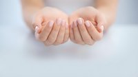 Open cupped hands gesture showing palms up in receiving position, soft lighting creates peaceful atmosphere for wellness and spiritual concepts.