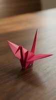 Red origami paper crane sitting on wooden table surface with soft natural lighting and blurred background for peaceful meditation and mindfulness concepts.