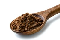Ground coffee powder in wooden spoon isolated on white background. Fresh roasted arabica coffee grounds with rich dark brown color and texture.