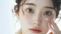 Young Asian woman with natural makeup and glowing skin touching face gently against white background, showcasing skincare and beauty concept.