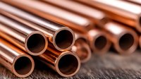 Shiny copper pipes and tubes arranged on rustic wooden surface showing industrial plumbing materials with circular hollow centers in warm metallic tones.