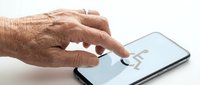 Senior adult hand with wrinkled skin touching smartphone screen, isolated on white background for accessibility and technology adoption concepts.