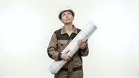 Young male construction worker of mixed ethnicity wearing hard hat and work uniform holding rolled architectural blueprints, isolated on white background for design projects.