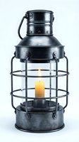 Vintage metal lantern with burning yellow candles inside protective wire cage, isolated on white background for home decor and lighting.