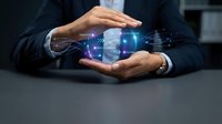 Businessman in dark suit holding glowing digital network interface with connected icons and data visualization between hands, representing technology innovation and business connectivity.