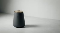 Modern black ceramic container with brass lid on neutral surface, suitable for home decor, product design, and lifestyle photography.