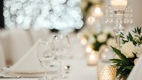 Elegant wedding table setting with wine glasses, candles and white flowers creating romantic dining atmosphere for special celebration events.