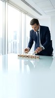 Professional businessman arranging wooden blocks with icons on modern office desk, strategic planning and business development concept for corporate presentations.