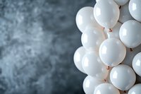White party balloons arranged in geometric pattern against textured gray background, creating minimalist composition with soft lighting and selective focus.