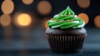 Chocolate cupcake with green frosting and sprinkles on dark background with golden bokeh lights. Holiday dessert with festive Christmas tree design decoration.