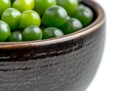 Fresh green grapes in rustic dark ceramic bowl against white background. Close-up view with selective focus highlighting natural texture and shine.