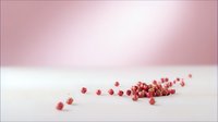 Pink peppercorns scattered on white surface with soft pink bokeh background creating minimalist culinary composition for food styling and design.