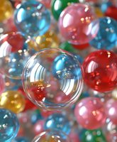 Colorful transparent glass or acrylic spheres with reflective surfaces creating dreamy bokeh effect, perfect for abstract backgrounds, holiday designs, and modern artistic compositions.