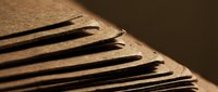 Stack of brown kraft paper sheets with curved edges creating dramatic shadows and depth for packaging and eco-friendly design projects.
