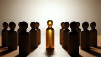 Golden figure stands out among dark silhouettes representing leadership, success, and standing apart from crowd in business concept.
