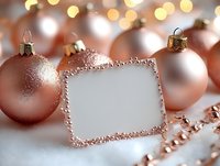 Rose gold Christmas baubles with blank greeting card on white snow background with festive bokeh lights and decorative beads for holiday design.