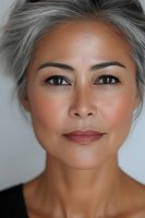 Close up portrait of mature Asian woman with silver gray hair and natural makeup showing confidence and grace against light background.