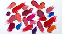 Colorful lipstick smears and swatches in various shades of red, pink, purple and orange on white background for beauty and cosmetics design.