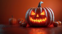 Glowing jack-o-lantern pumpkin with carved scary face on orange background with small pumpkins for Halloween decoration and autumn seasonal design.