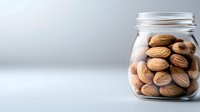 Fresh almonds stored in clear glass jar on white background, showcasing natural healthy snack for nutrition and cooking ingredients.