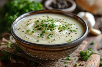 Creamy mushroom soup garnished with fresh chopped herbs in rustic ceramic bowl. Close-up view of homemade comfort food with selective focus and natural lighting.