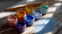 Colorful art paint jars with brush on wooden surface in natural sunlight with window shadow pattern creating artistic composition for creative projects.