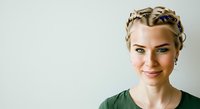 Young woman with blonde braided hair and fair complexion wearing green shirt, smiling at camera against white background. Portrait suitable for business, lifestyle, and professional applications.