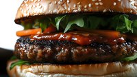 Juicy grilled beef burger with fresh lettuce, tomatoes and sauce on toasted sesame bun, extreme close up macro shot showing texture and ingredients.
