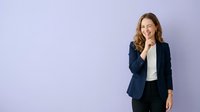 Smiling young woman with long brown hair wearing navy blazer and white shirt against purple background, suitable for corporate and business marketing materials.