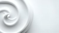 White cream swirl texture with smooth flowing curves creating elegant spiral pattern on clean background for cosmetic and skincare product design.