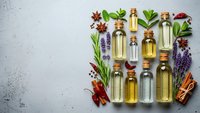 Natural essential oils in glass bottles with fresh herbs and spices on white background. Aromatherapy, spa wellness, organic skincare ingredients flat lay.