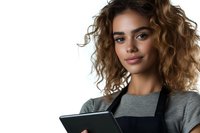 Young mixed race woman with curly hair wearing gray top and black apron holds digital tablet, looking confidently at camera against white background.