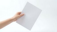 Hand holding blank white paper sheet against clean background for mockup design templates and presentations.