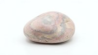 Natural pink granite stone with smooth surface isolated on white background for geology education and mineral collection displays.