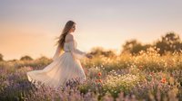 Young woman with long brown hair, fair complexion, wearing flowing white dress standing in lavender field during golden hour sunset, wind blowing hair, peaceful countryside landscape with warm natural lighting.