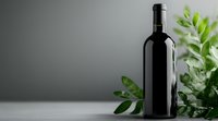 Dark wine bottle against gray background with fresh green leaves, minimalist composition for wine industry, restaurant menu, and beverage marketing.