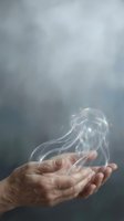 Elderly hands cupping translucent smoke with rainbow light reflections against soft gray background for spiritual and wellness concepts.