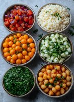 Healthy Mediterranean meal prep bowls with chickpeas, quinoa, cherry tomatoes, herbs and fresh vegetables arranged in wooden containers for balanced nutrition.