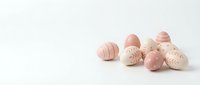 Pastel pink Easter eggs with delicate floral patterns arranged on white background. Spring holiday decoration concept for greeting cards and seasonal designs.