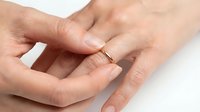 Close-up of two hands exchanging a delicate gold wedding band, symbolizing marriage commitment and engagement. Suitable for wedding invitations, jewelry marketing, and relationship content.