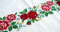 Traditional Ukrainian embroidery with colorful floral pattern on white linen fabric. Handcrafted cross-stitch roses and leaves for cultural textile design.