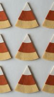 Felt candy corn triangles arranged in rows on neutral background for autumn Halloween crafts and seasonal decorating projects.