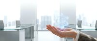 Businessman hand holding glowing holographic cube with network connections in modern office, representing digital innovation and technology.