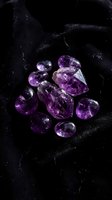 Purple amethyst gemstones collection on dark marble surface for luxury jewelry design and healing crystal meditation practices.