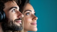 Young Caucasian couple with bearded man wearing headphones and woman looking up with dreamy expressions against blue background, profile view showing peaceful contemplative mood.