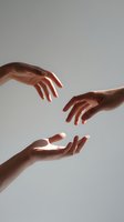 Three hands reaching toward each other against neutral gray background, symbolizing connection, support, and human relationship in minimalist composition.