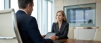 Middle-aged Caucasian woman in business attire conducting job interview with male candidate in modern office setting. Professional recruitment and hiring concept.
