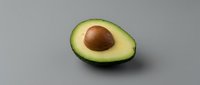 Fresh ripe avocado half with pit on neutral background for healthy cooking and nutrition concepts.